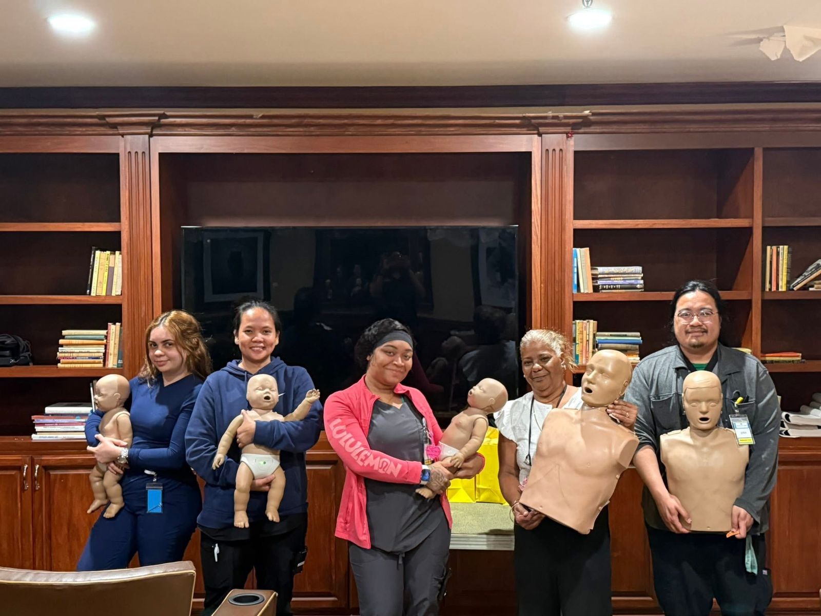 Breathe Again CPR students holding adult and infant training manikins after class.