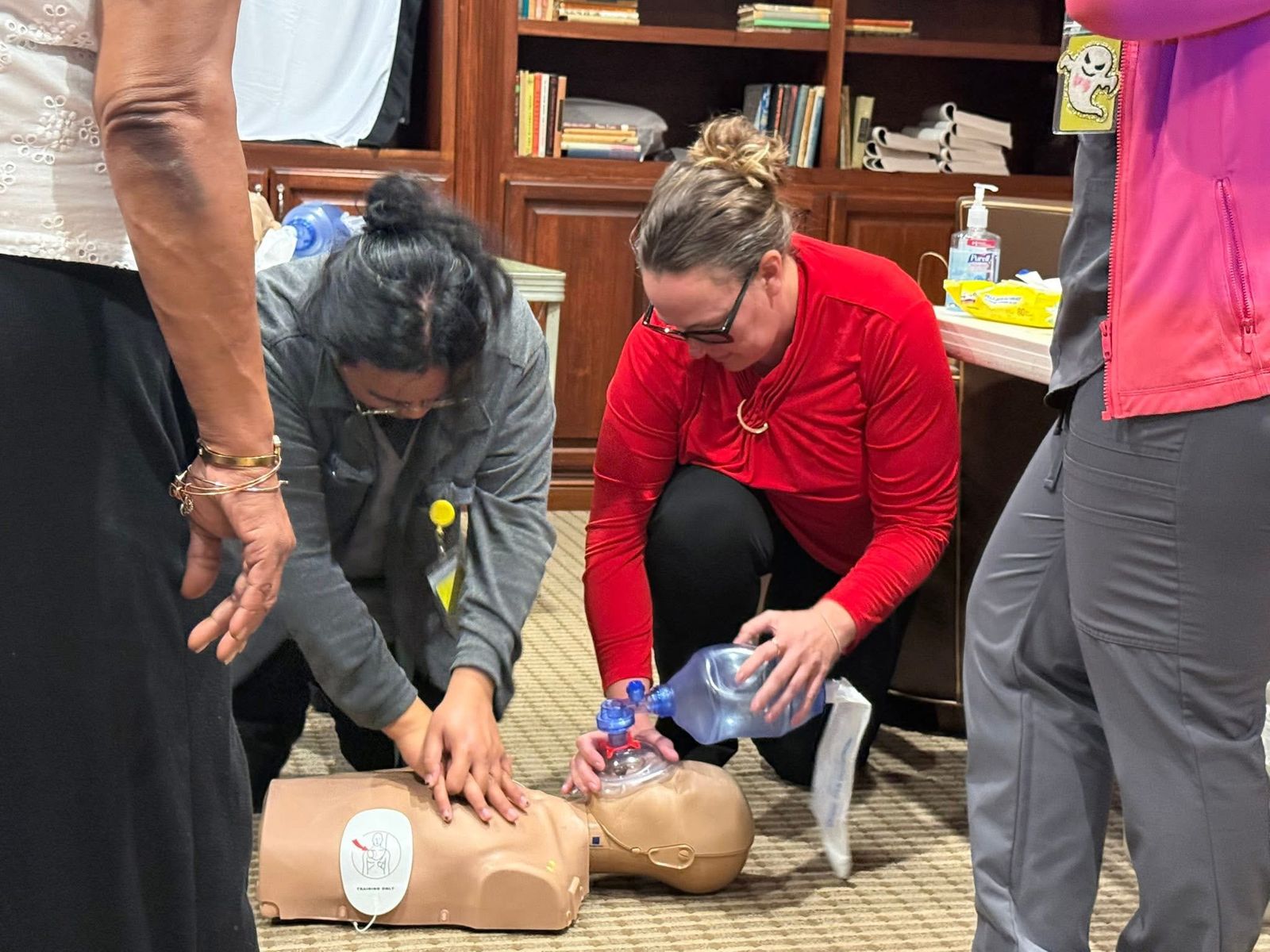 Two students practicing chest compressions and bag-mask breaths on a CPR manikin.
