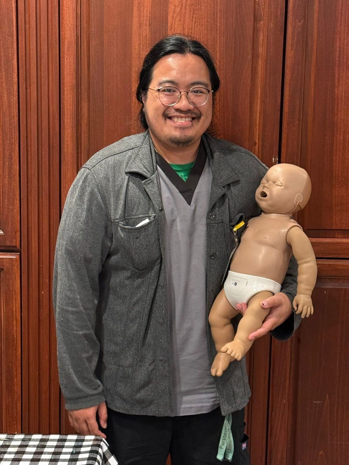 A student holding an infant CPR manikin.